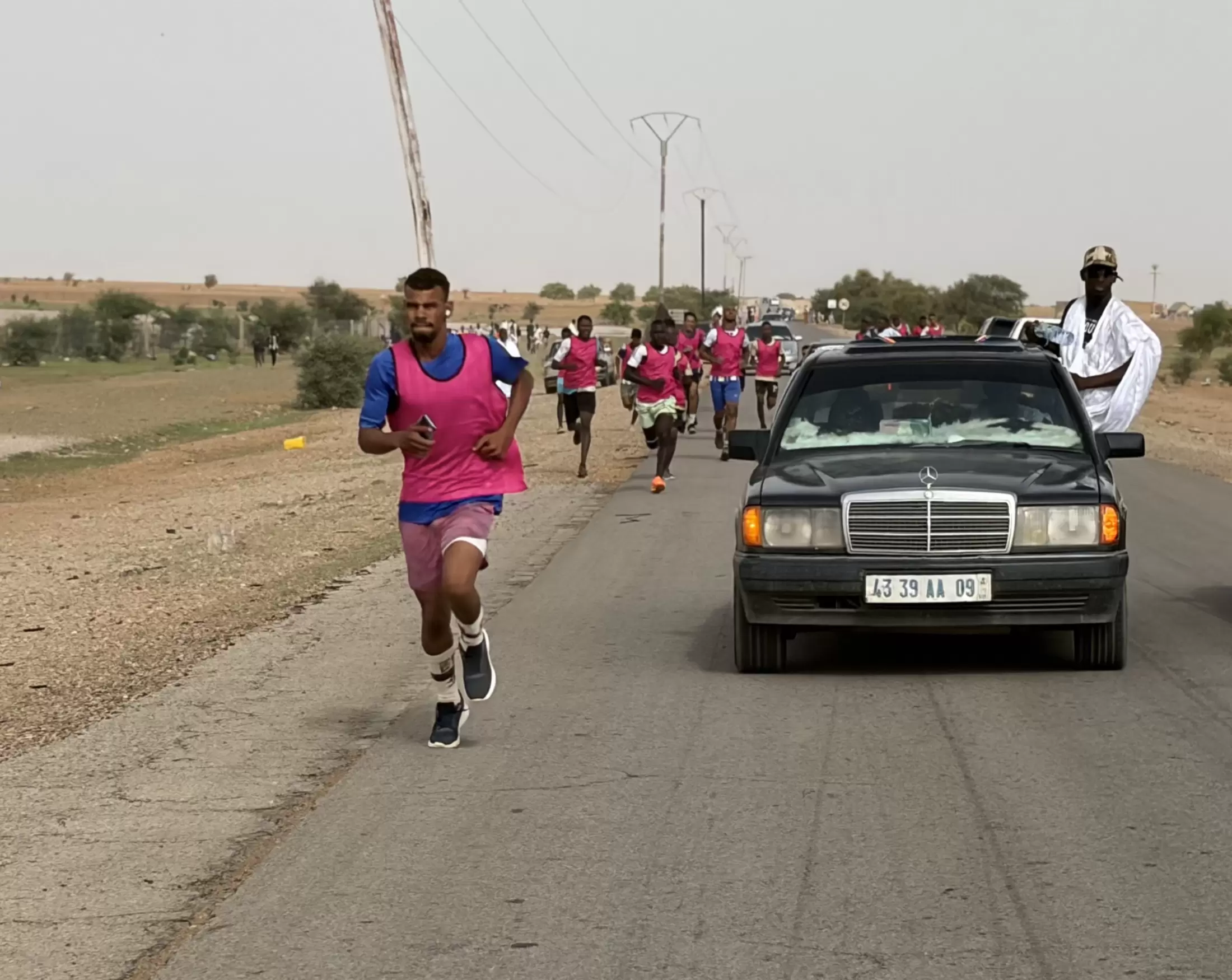 La voiture ouvreuse et les premiers coureurs, sur l’asphalte.