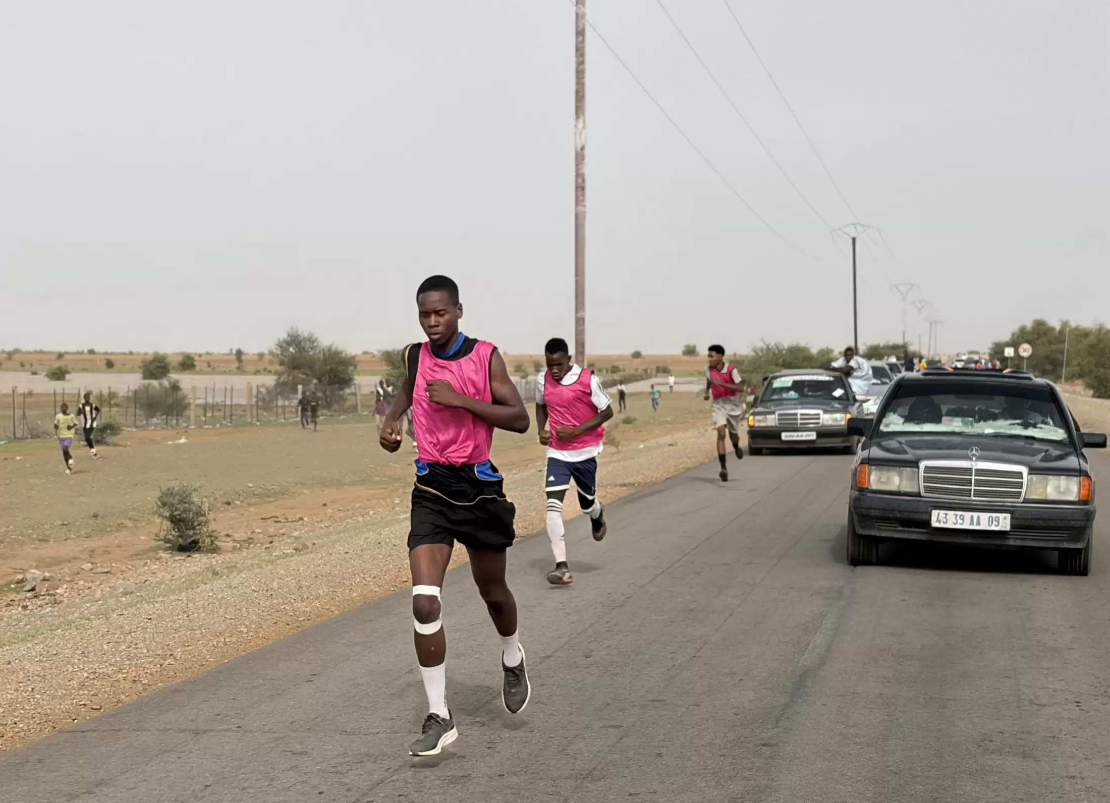 Le premier coureur devance le groupe, suivi par la voiture de l’organisation.
