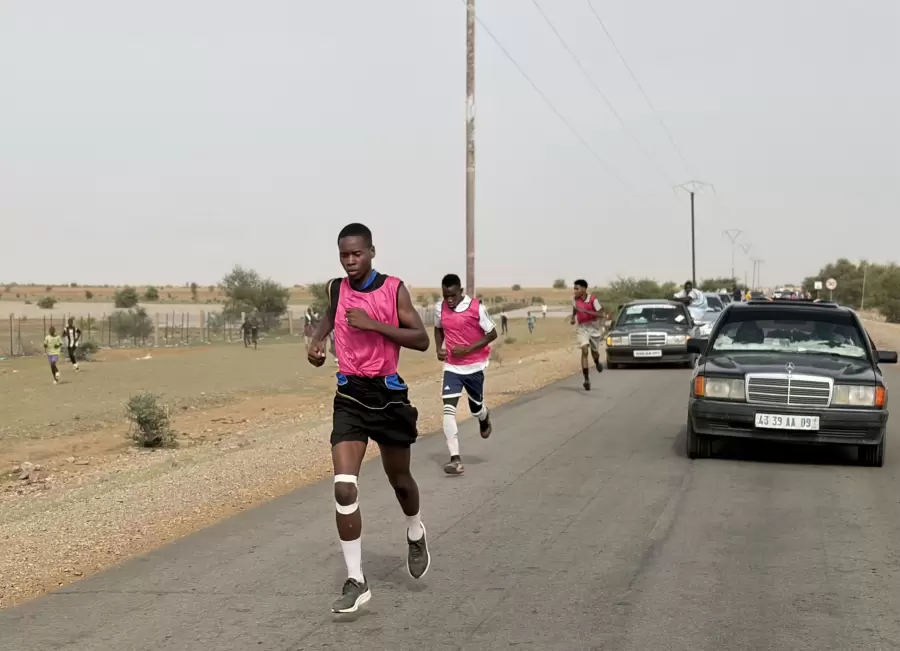 Le premier coureur devance le groupe, suivi par la voiture de l’organisation.
