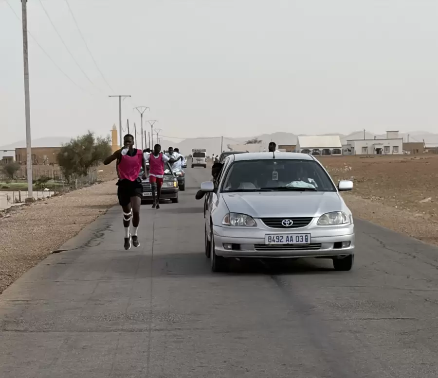 Les coureurs encadrés par les voitures sur la route de la ville.