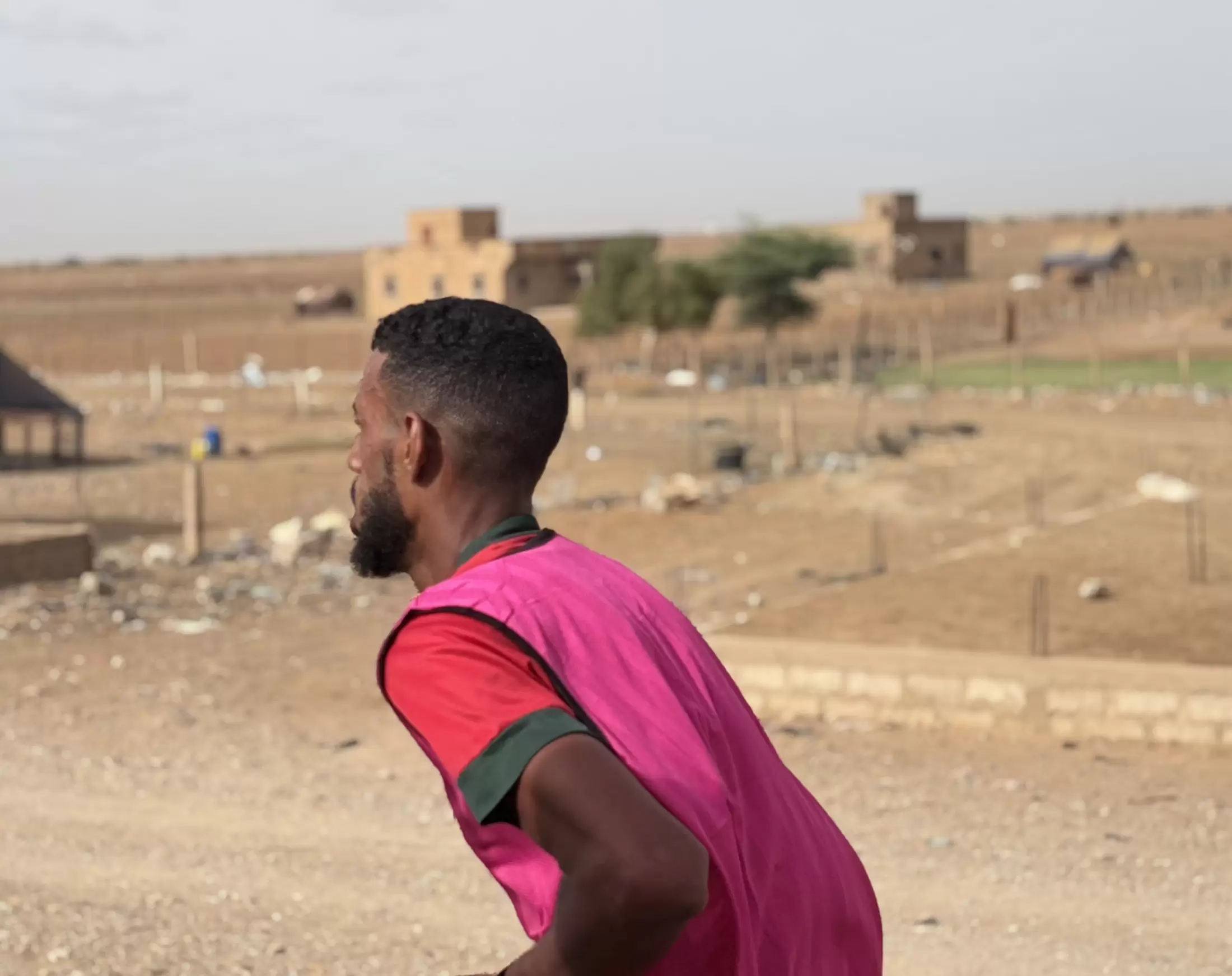 Un coureur de dos, face aux maisons basses qui bordent la route.