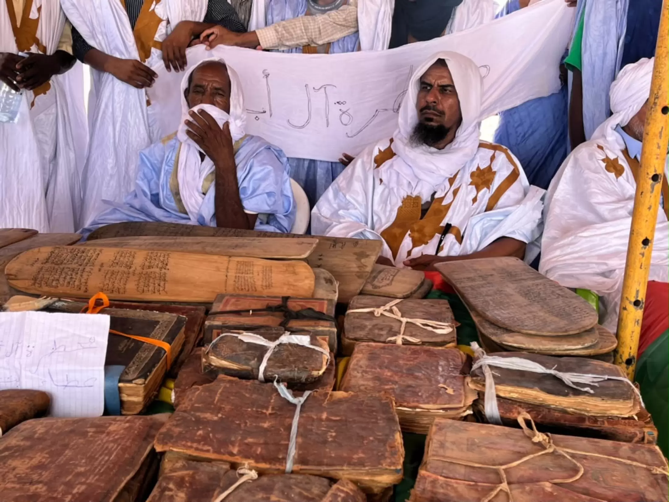 Des manuscrits reliés de cuir, présentés par leurs gardiens.