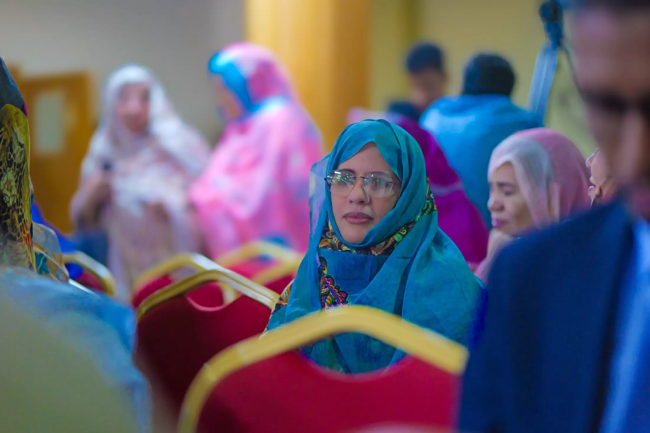 Une invitée en voile turquoise, au milieu d’une salle en couleurs.