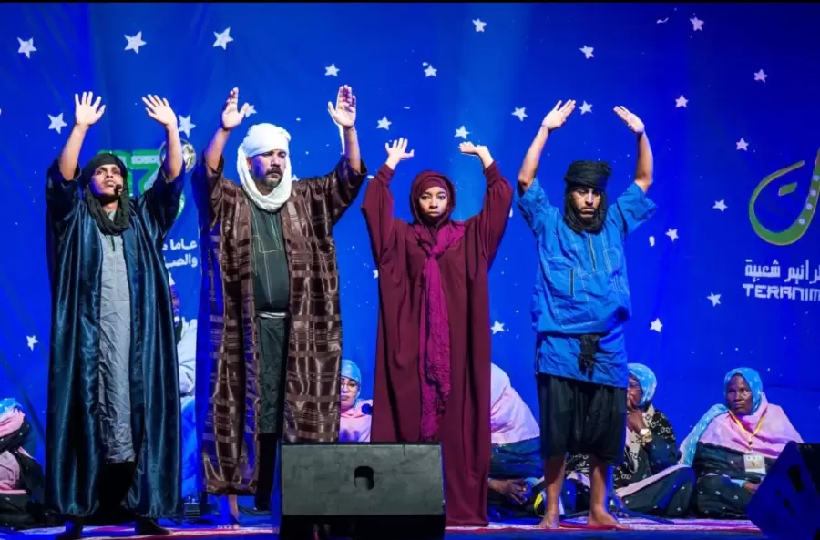 Une troupe lève les bras à l’unisson sous les étoiles du décor.