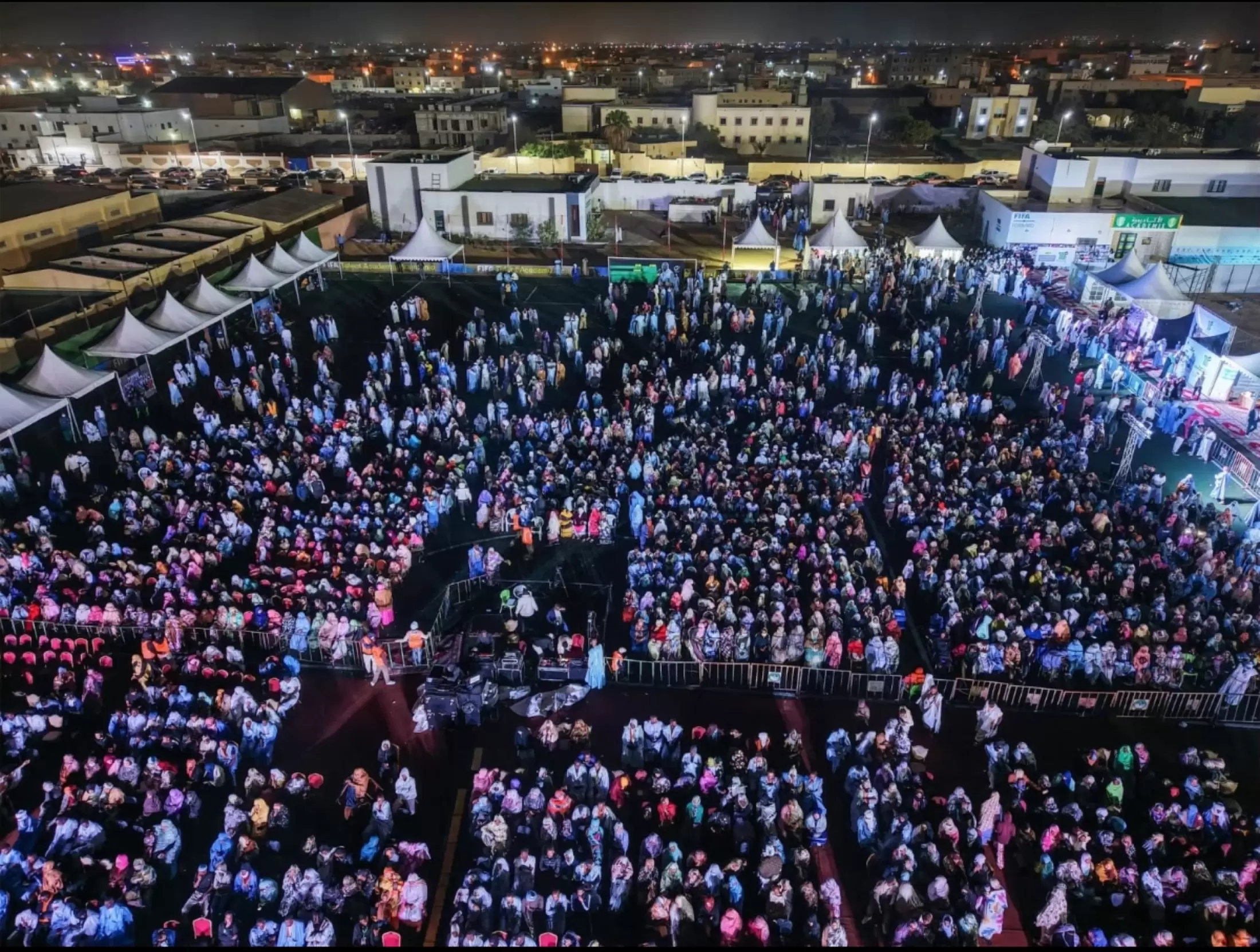 Vue aérienne d’un rassemblement nocturne sur une place illuminée.