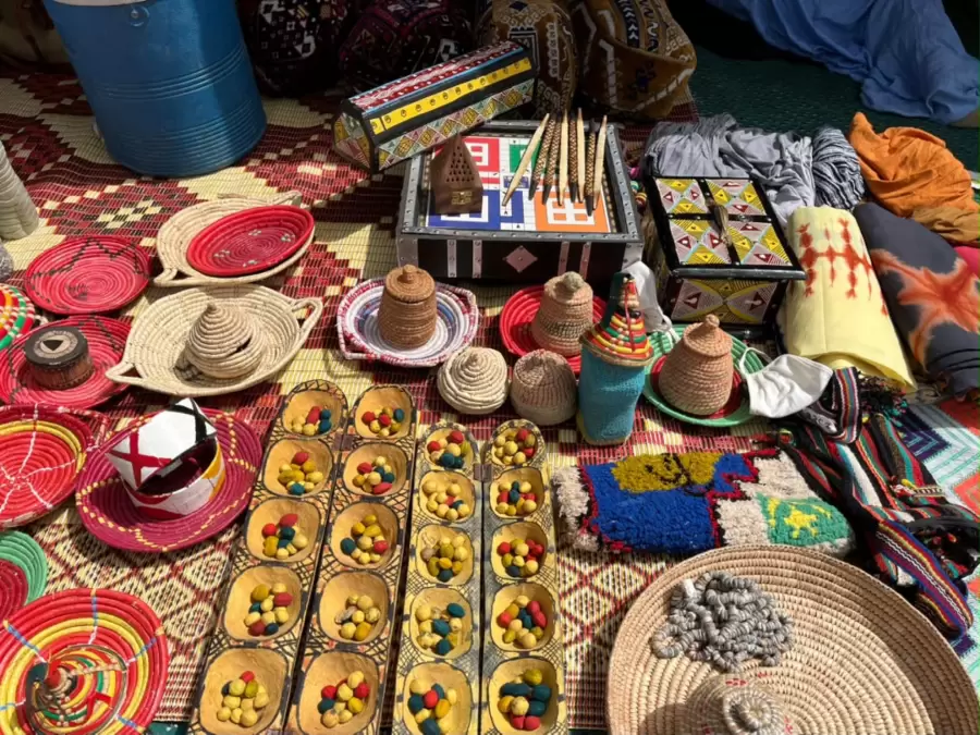 Plateaux tressés, perles et plateau de jeu sur un tapis rouge.